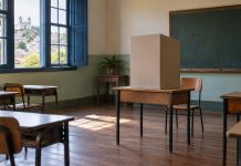 Sala de escola preparada como seção eleitoral, com cabine de votação sobre a mesa
